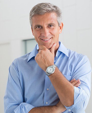 White older man with watch crossing his arms and smiling at the camera