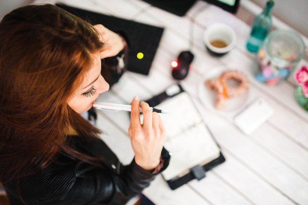 Woman at Desk with Pen in Her Mouth