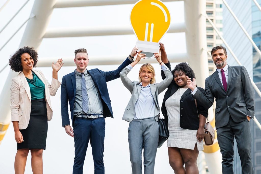 Group of coworkers smiling and holding a cardboard