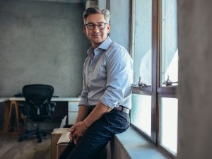 image of a mature businessman leaning on a windowsill.