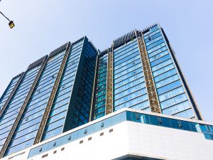 image of blue sky reflecting on glass and steel multi-story office building.